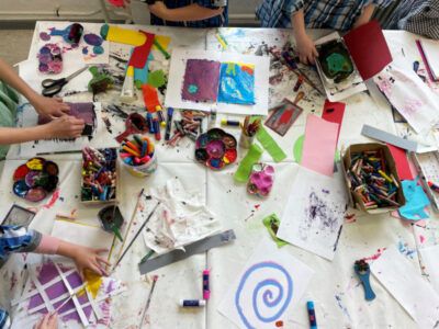 Kreativer Kindertisch: Farben, Pinsel, Papier. Kunstprojekt mit Kindern. Bunte Malutensilien für junge Künstler.