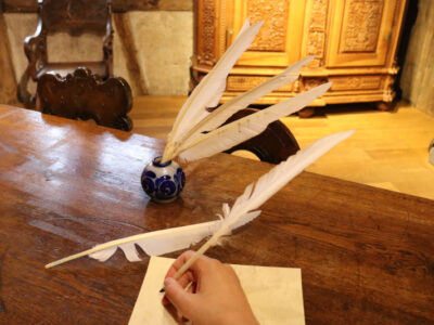 Federkiel und Tinte auf Holzschreibtisch. Schreiben mit Feder, historisch.