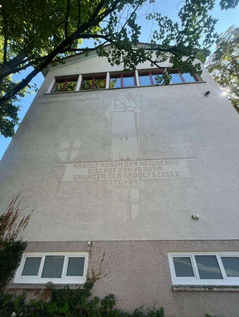 Radolfzeller Schule Fassade. Wandbild von Rudolf, Mönch und Bischof, Gründer der Radolfszelle. Architektur und Geschichte.